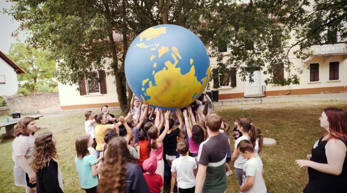 Kinder stemmen gemeinsam einen riesigen Erdball