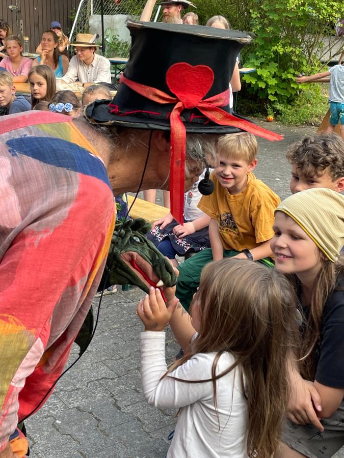 Micha mit Zylinder zeigt einer Kindergruppe den Drachen