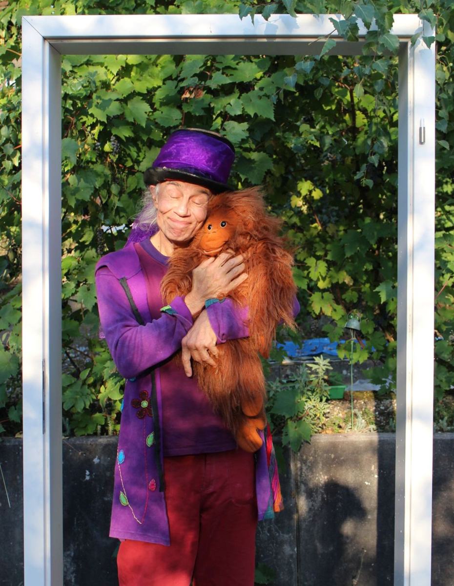 Micha mit lila Zylinder umarmt mit geschlossenen Augen einen Plüsch-Orang-Utan