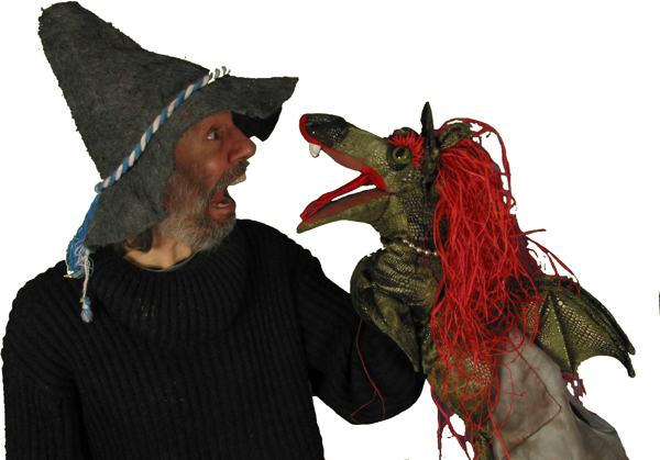Micha mit Filzhut staunt eine Drachenpuppe mit roter Mähne an
