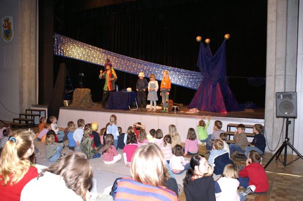 Bühne im Saal mit Sternenstoff, Micha und drei Kinder, davor das Publikum