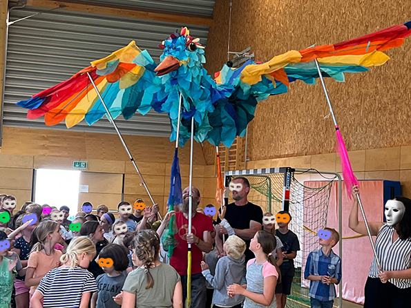 Der große bunte Friedensvogel in einer Turnhalle mit Kindern